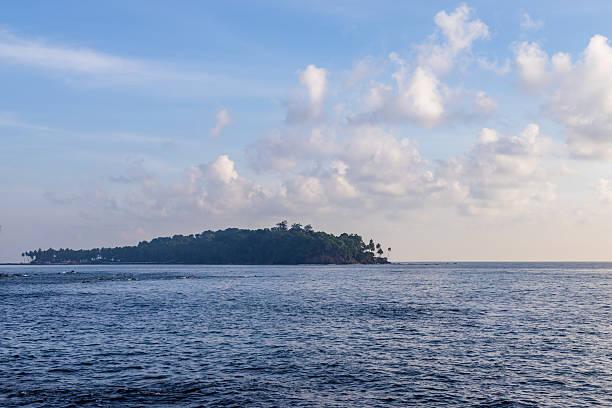 istock calm ocean and remote tree-covered island beneath gentle clouds 2242945831