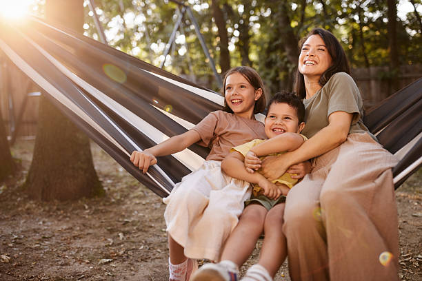 istock Cheerful mother and kids having fun in hammock at the backyard. 2242946022