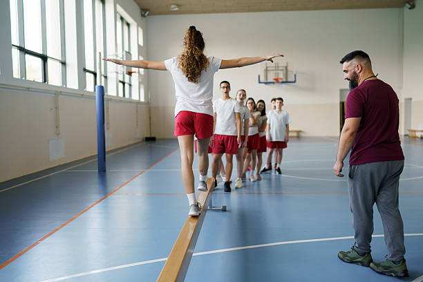 istock Teacher monitoring students balancing on beam during physical education 2242947201