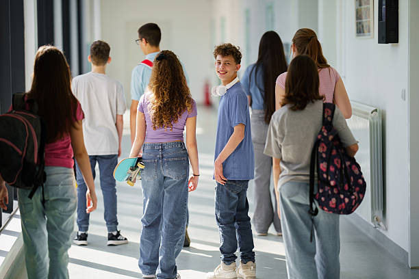 istock Teenagers walking in school hallway, smiling and talking 2242948307
