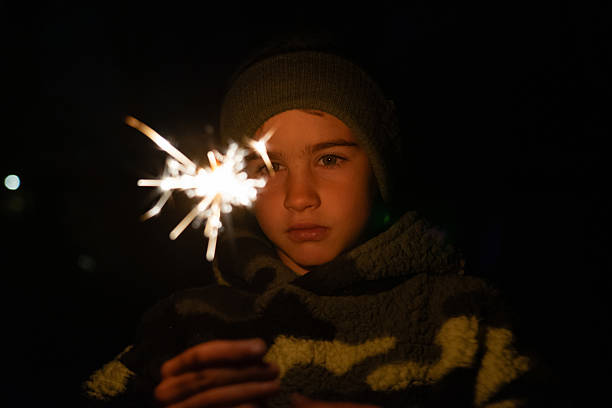 istock Boy holding sparkling sparkler in darkness during celebration 2242948755