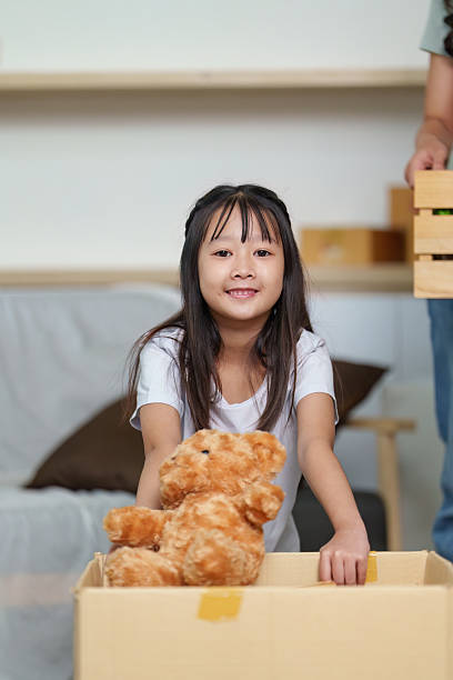 Family bonding during moving day. Young girl helping with unpacking boxes.