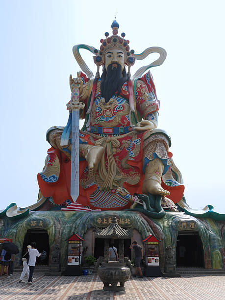 Kaohsiung, Taiwan - November 11 2024: Frontal view of the majestic Xuantian Shangdi statue, showing the temple entrance at the base and a large incense burner in the foreground.