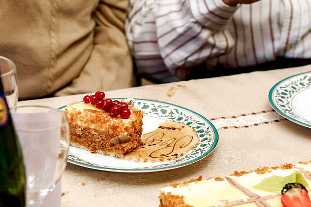 Close-up of a festive cake slice with red currants on a patterned plate during a family celebration. Symbol of sharing, sweetness, and convivial moments.