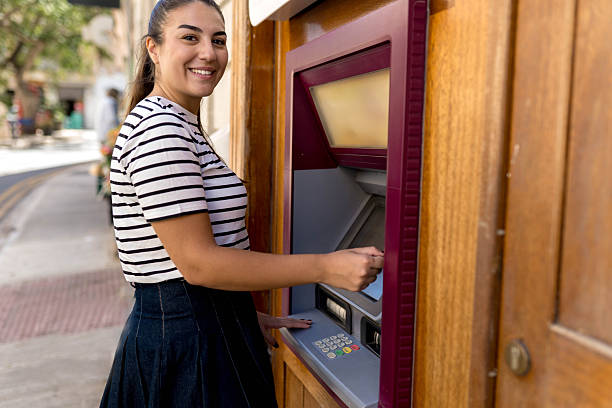 istock Woman withdrawing cash from atm and smiling 2242958978