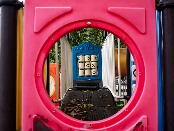 Abandoned Old Playground Equipment Viewed Through Red Frame - Neglected Children's Play Area with Overgrown Trees