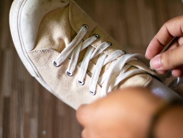 istock Close up hands tying white canvas sneakers shoelaces getting ready to go out or exercise 2242960283