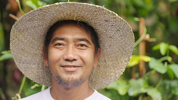 istock smiling southeast asian man farmer, straw hat looking at camera in field 2242961510