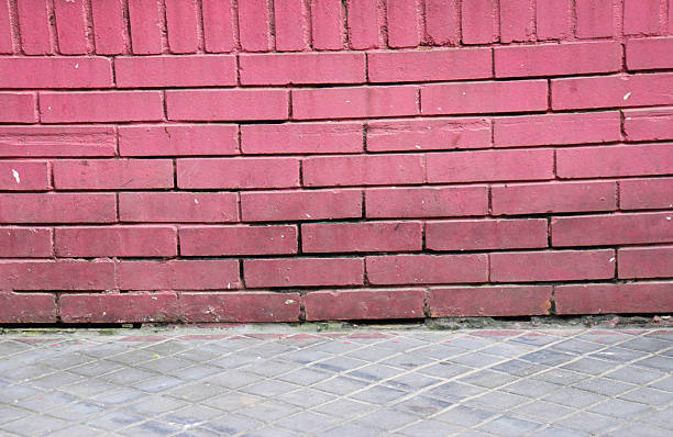 istock Closeup view of a textured red brick wall with a grey concrete floor 2242968983