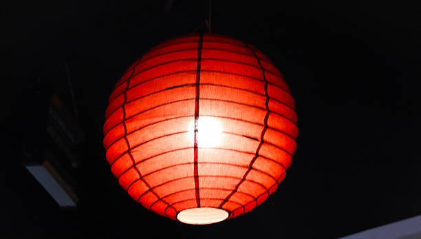A bright red paper lantern glows warmly against a dark background, creating a cozy ambiance