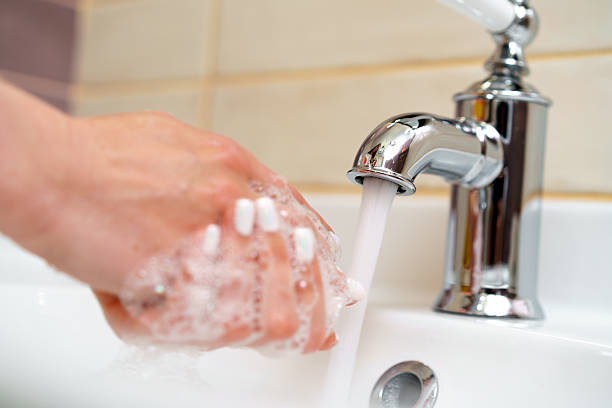 Woman washing her hands with soap in bathroom close up