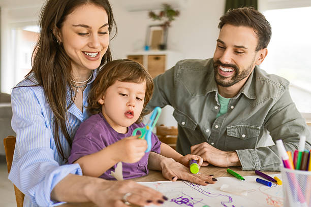 istock Parents Helping Child Cutting With Scissors at Table 2242972252