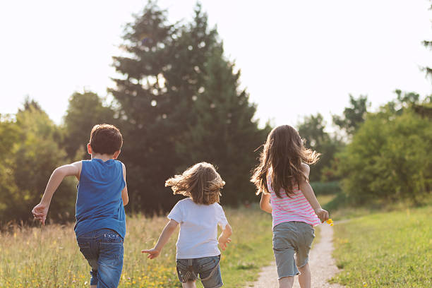 istock Kids Running Through Field at Sunset 2242972732