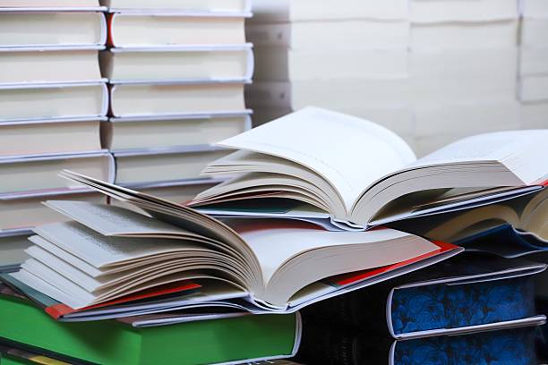 istock stack of books, close up. Open book on the table in library. Back to school concept. Open book on table with blur bookshelf background 2242974359