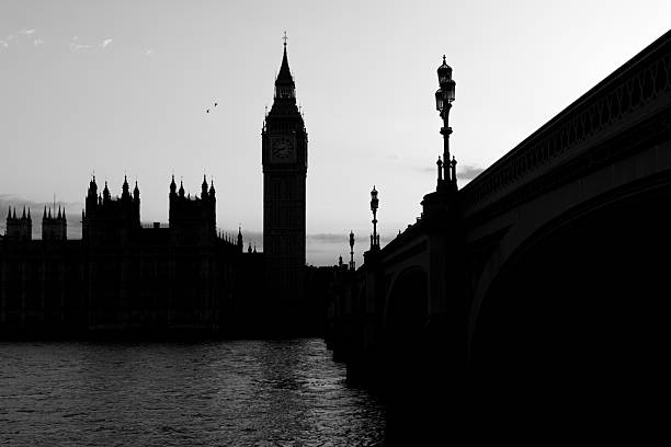 Elizabeth Tower and the Houses of Parliament with Westminster Bridge at dusk in monochrome. Strong contrast and calm river surface create a classic city scene.