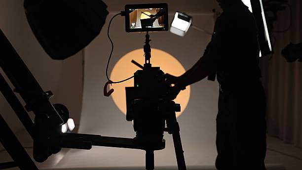 istock Professional studio for photo video filming with modern lighting equipment and large white cyclorama, assistant holding and clapping in clapperboard. 2242980035