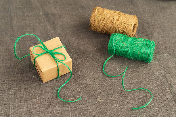 istock A small gift box wrapped in plain brown craft paper is tied with green thread in a bow. 2242980252