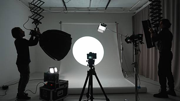 istock Professional studio for photo video production filming with modern lighting equipment large white cyclorama, photographer and assistant setting up lights and camera. 2242984341