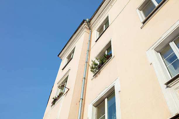Bright day over a pastel colored building with plants