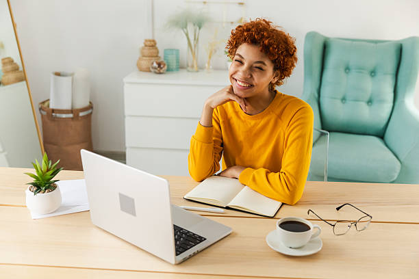 istock Smiling African American girl using laptop at home office typing chatting reading writing email. Young woman having virtual meeting online chat video call conference. Work learning from home. 2242991749