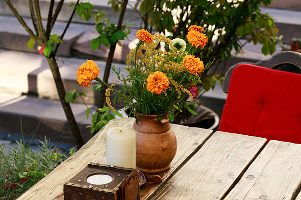 Elegant tabletop decor featuring two candles and a floral centerpiece on a reflective marble surface, creating a cozy ambiance with city lights blurred in the background.