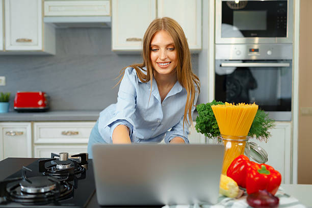 istock Young blonde woman with long hair using laptop in a kitchen 2242995330