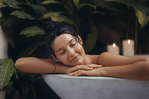 istock Serene Woman Relaxing in Luxury Bath Amidst Lush Greenery and Candlelight 2243000956