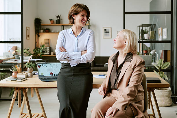 istock Two Middle Aged Women Smiling and Talking in Modern Office Workspace 2243003199