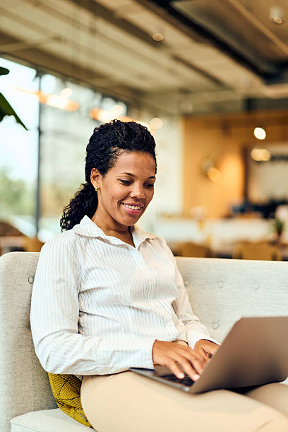 istock African-American Woman Enjoying Work On Laptop While Relaxing On Couch In Modern Office Space 2243003738