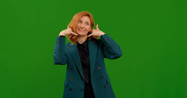 istock Woman shows playful gestures in studio with green background during daytime 2243005958