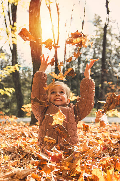 istock adorable happy boy playing with fallen leaves in autumn park 2243008325