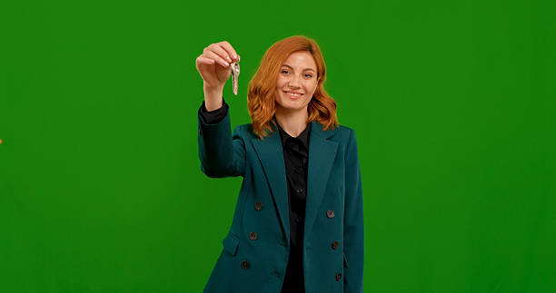 istock Woman raising keys boasting about new home on green screen isolate background. 2243012538