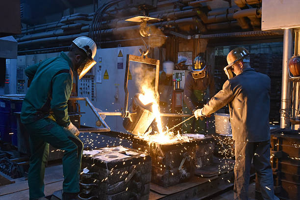 istock Group of workers in an iron foundry - casting a workpiece with liquid hot metal into a mold - cooperation and work safety 2243013989