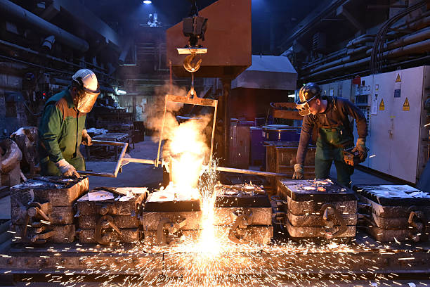 istock Group of workers in an iron foundry - casting a workpiece with liquid hot metal into a mold - cooperation and work safety 2243014031