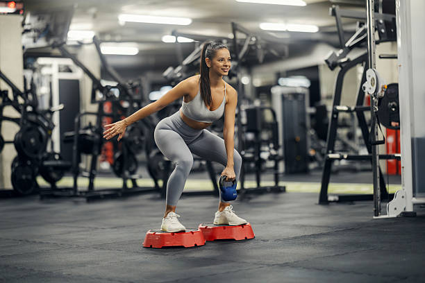istock Woman exercising squatting with kettlebell on aerobic step in gym 2243015491