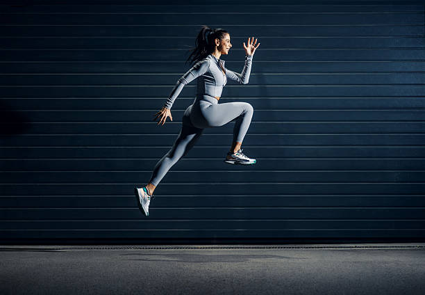 istock Woman in activewear jumping against dark wall 2243015616