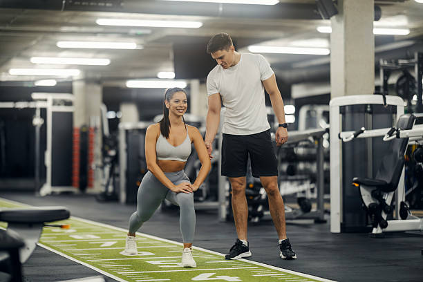 istock Woman stretching in gym with personal trainer coaching 2243015970