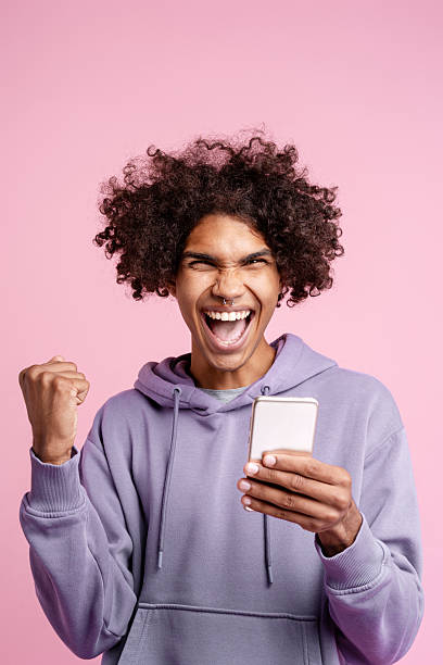 istock Young man celebrating victory looking at phone 2243016418