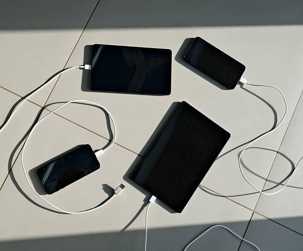 istock Digital tablets and mobile phones with charger cables on tiles floor with sunlit shadows 2243016456