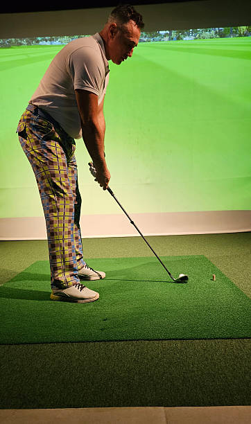 istock Golfer prepares to swing on an indoor driving range with a digital screen a golf course 2243023179
