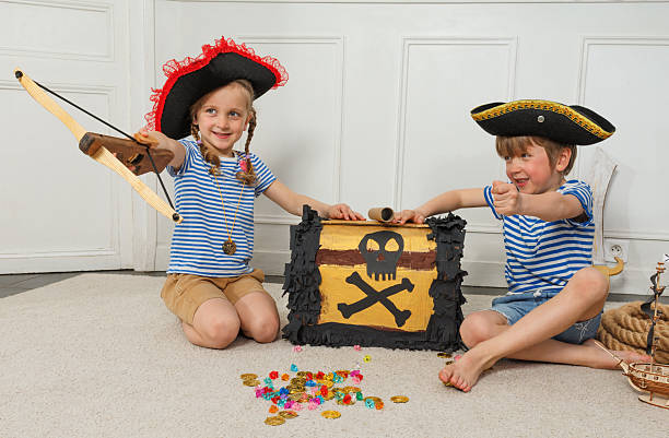 istock Pirate kids aim bow and arrow by a skull-marked treasure chest 2243024580
