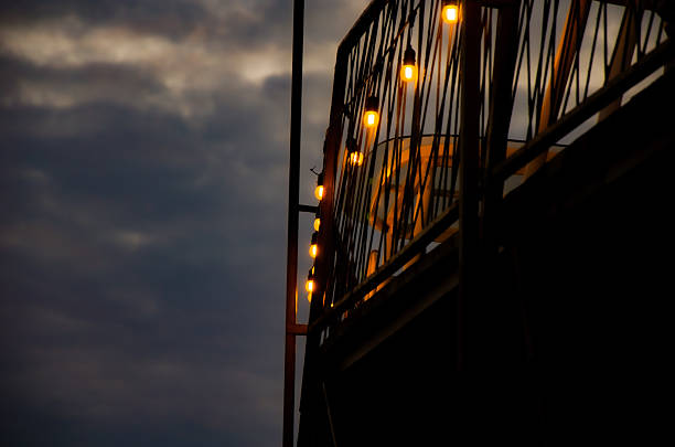 istock Warm Edison Bulbs on Balcony Railing Against Dark Twilight Sky 2243024590
