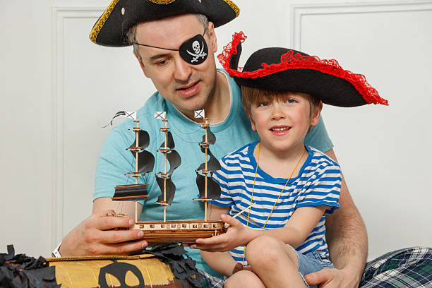 istock Pirate playtime: father with son play in ship model and chest 2243024624