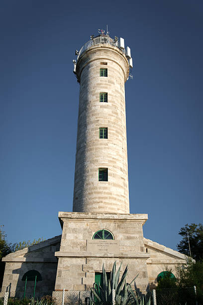 istock Stone lighthouse with antennas against a clear blue sky. 2243024988