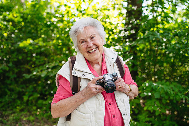 istock Elderly woman photographing nature during forest walk. 2243034833