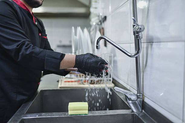 istock Worker Washing ingredients at Kitchen Sink in Gloves During Food Preparation Process 2243034856