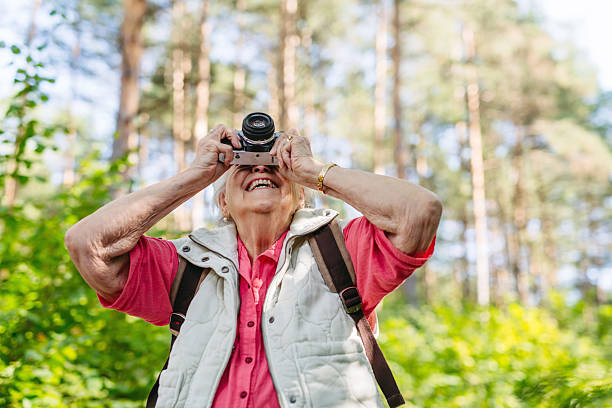 istock Elderly woman photographing nature during forest walk. 2243035320