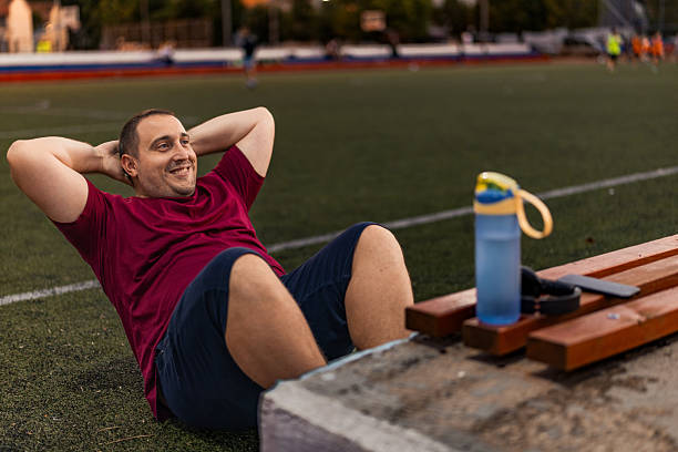 istock Overweight man doing abdominal exercise on the sport field. 2243035360