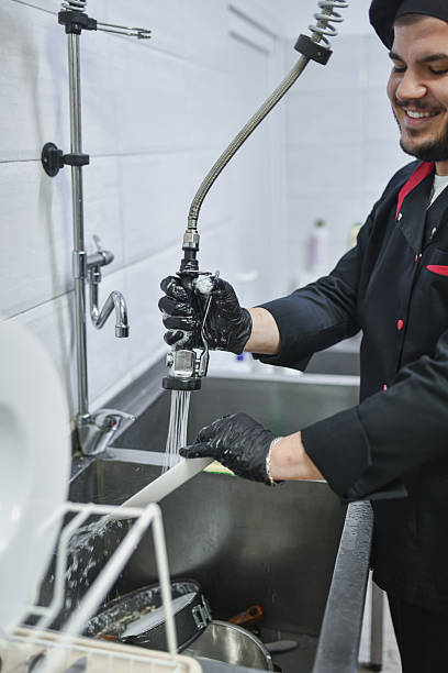 istock Professional Worker Washing Dish With Sprayer At Kitchen Sink In Gloves 2243035503