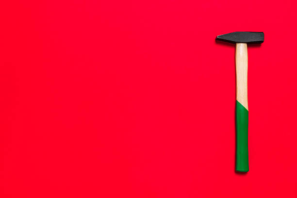 Hammer is isolated on a red background with place for text. Shop banner with construction tools. New Year or Christmas festive backdrop. One of the basic home use instrument for hammering nails.